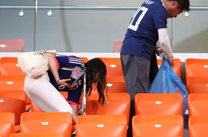 Aksi fans Jepang saat memungut sampah di tribun stadion.