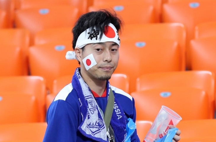 Aksi salah satu fans Jepang saat memungut sampah di tribun stadion.