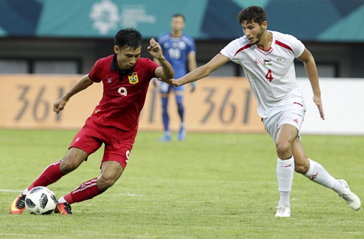 Pemain timnas Laos Soukchinda Nathasouk (kiri) berebut bola dengan pemain Palestina Michelmilad Termanini pada pertandingan Grup A Asian Games ke-18 di Stadion Patriot, Bekasi Minggu (12/8). (ANTARA/INASGOC/Jessica Margaretha)