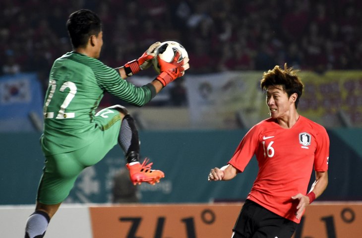 Penyerang Korea Selatan Hwang UI Jo (kanan) berebut bola dengan penjaga gawang Malaysia Muhammad Haziq Nadzli (kiri) saat menjalani babak penyisihan cabang olahraga sepak bola Asian Games group C antara Korea Selatan melawan Malaysia di Stadion Jalak Harupat, Kabupaten Bandung, Jawa Barat, Kamis (16/8). (INASGOC/Bukbis Candra Ismet Bey)