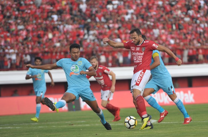 Pemain Bali United Ilija Spasojevic berebut bola dengan pesepak bola Persela Lamongan, Arif Satria (kiri) dalam Pertandingan Sepak Bola Liga 1 2018 di Stadion I Wayan Dipta, Gianyar, Bali, Selasa (11/9). Bali United menang atas Persela dengan skor 3-2. (ANTARA FOTO/Nyoman Budhiana)