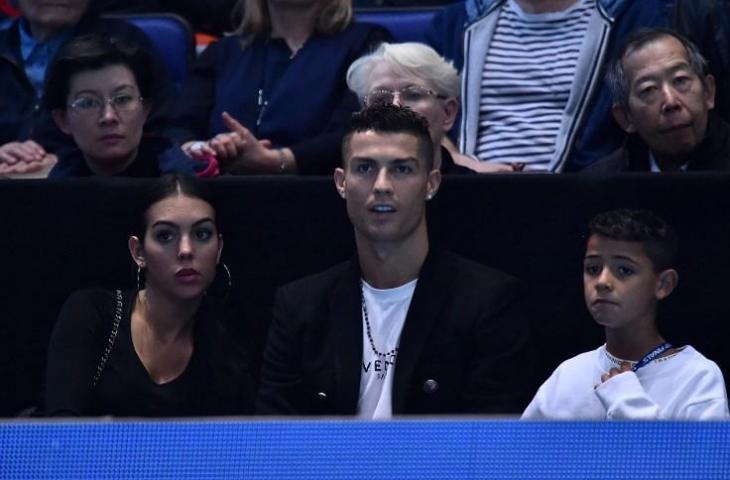 Georgina Rodriguez, Cristiano Ronaldo, dan Cristiano Ronaldo Jr saat menyaksikan laga tenis  Novak Djokovic vs ohn Isner pada 12 November 2018 (Glyn Kirk/AFP)