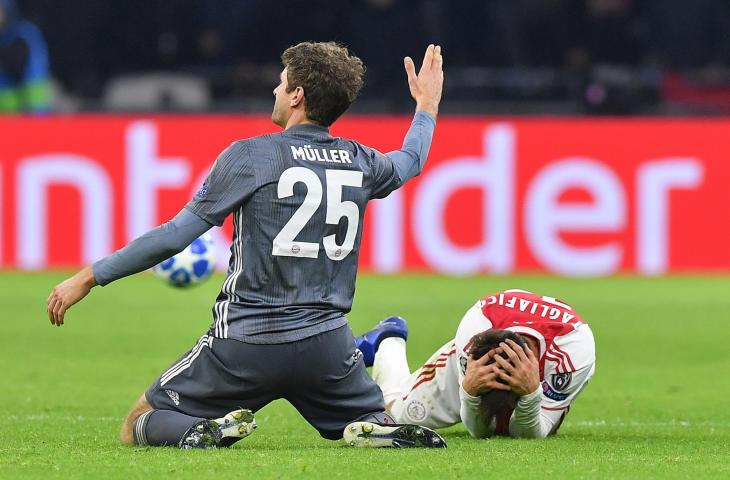 Pemain Bayern Munchen, Thomas Mueller usai menendang kepada pemain Ajax Amsterdam, Nicolas Tagliafico saat laga babak penyisihan grup Liga Champions 2018 di Johan Cruyff Arena (12/12/2018)