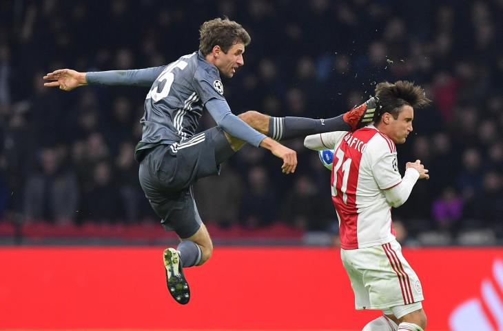 Pemain Bayern Munchen, Thomas Mueller menendang kepada pemain Ajax Amsterdam, Nicolas Tagliafico saat laga babak penyisihan grup Liga Champions 2018 di Johan Cruyff Arena (12/12/2018)