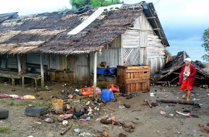 Warga berjalan di samping atap rumah miliknya yang roboh setelah diterjang gelombang tinggi di Kampung Cikadu, Kecamatan Tanjung Lesung, Pandeglang, Minggu (23/12/18). BPBD setempat melaporkan jumlah korban meninggal dunia 13 orang dan ratusan lainya mengalami luka-luka serta 400 lebih rumah warga di pinggir pantai roboh akibat terjangan gelombang pasang dan ombak setinggi hingga 5 meter Sabtu (22/12) malam. (ANTARA FOTO/Muhammad Bagus Khoirunas)