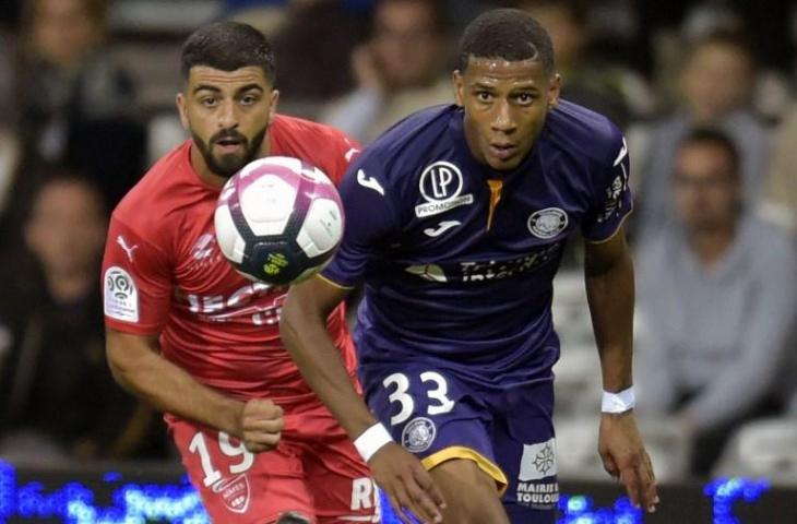 Pemain bertahan Toulouse, Jean-Clair Todibo (kanan) berebut bola dengan penyerang Nimes, Umut Bozok (kiri). [PASCAL PAVANI / AFP]