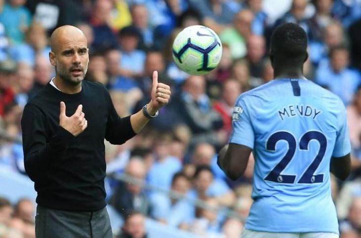 Pelatih Manchester City, Pep Guardiola memberikan bola kepada Benjamin Mendy pada laga melawan Huddersfield Town pada 19 Agustus 2018 (Lindsey Parnaby/AFP)