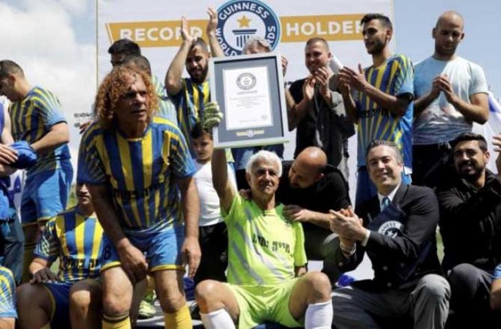 Isaak Hayik (tengah) berpose dengan kenang-kenangan Guinness World Record setelah secara resmi menjadi pesepakbola tertua di dunia. (Reuters)