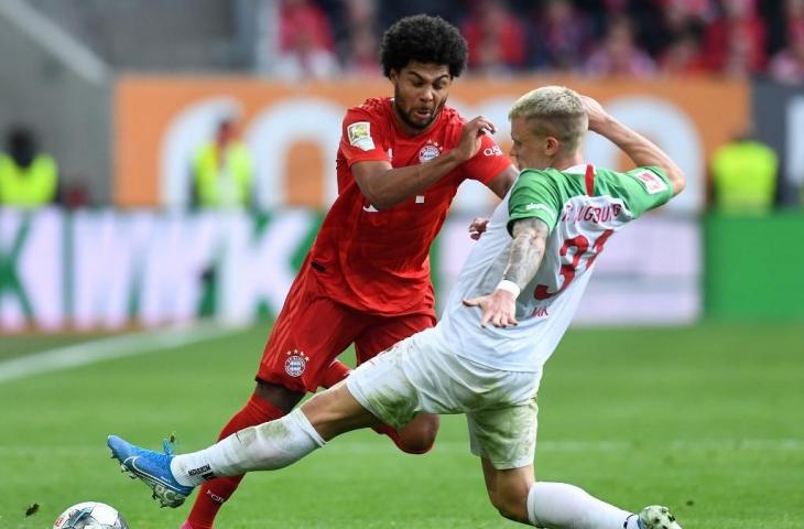 Gelandang Bayern Munich, Serge Gnabry berduel dengan bek Augsburg, Philipp Max pada gelaran Liga Jerman 2019/20 di Stadion WWK Arena, Sabtu (19/10/2019). [CHRISTOF STACHE / AFP]