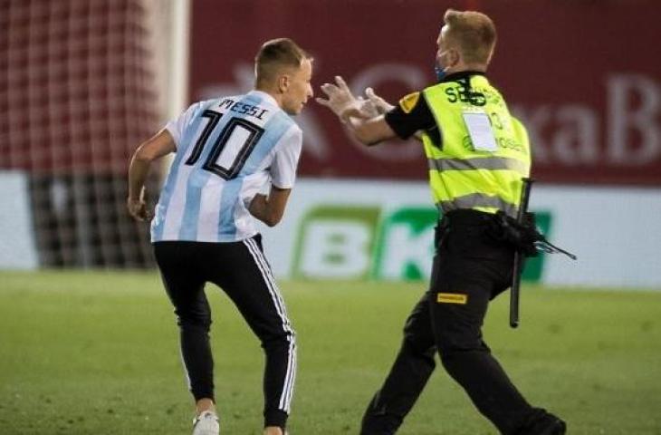 Seorang penggemar Lionel Messi (kiri) merangsek masuk ke lapangan Estadi de Son Moix di Palma de Mallorca, Minggu (14/6/2020) dini hari WIB, saat Real Mallorca menghadapi Barcelona di laga Liga Spanyol 2019/2020. [JAIME REINA / AFP]