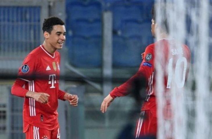 Gelandang Bayern Munich, Jamal Musiala melakukan selebrasi dengan Leroy Sane setelah mencetak gol kedua timnya dalam laga leg pertama babak 16 besar Liga Champions antara Lazio vs Bayern di Stadion Olimpico, Roma, Rabu (24/2/2021) dini hari WIB. [Alberto PIZZOLI / AFP].