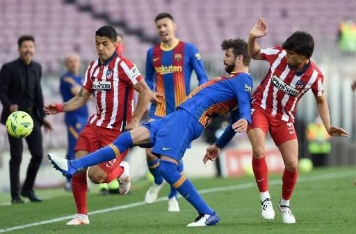 Luis Suarez berduel dengan Gerard Pique di laga Barcelona vs Atletico Madrid. (Josep LAGO / AFP)