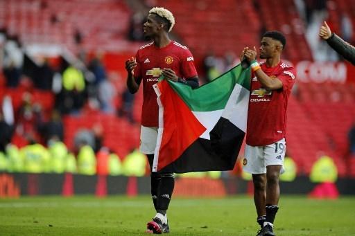 Paul Pogba dan Amad Diallo kibarkan bendera Palestina. (PHIL NOBLE / POOL / AFP)