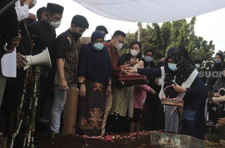 Keluarga menaburkan bunga di makam legenda bulutangkis Indonesia, Markis Kido di TPU Kebon Nanas, Cipinang, Jakarta, Selasa (15/6/2021). [Suara.com/Angga Budhiyanto]