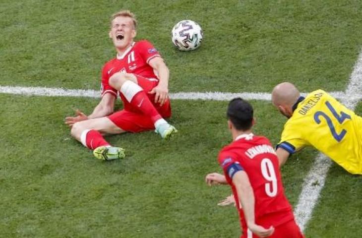 Bek Swedia, Marcus Danielson, melanggar striker Polandia, Karol Swiderski. (Maxim Shemetov/AFP)