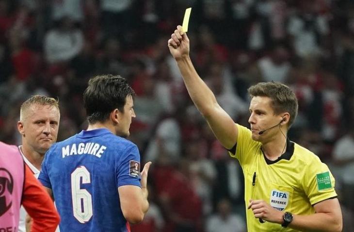 Wasit Daniel Siebert memberikan kartu kuning untuk Kamil Glik Harry Maguire dalam laga Polandia vs Inggris Kualifikasi Piala Dunia 2021. (JANEK SKARZYNSKI/AFP)