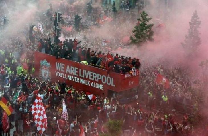 Para pemain Liverpool melambaikan tangan kepada para suporter dari bus terbuka selama parade melalui jalan-jalan Liverpool, Inggris pada 29 Mei 2022, untuk merayakan kemenangan Piala Liga dan Piala FA 2021-22. (AFP)