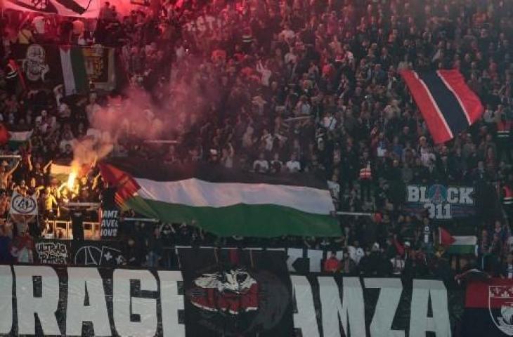 Suporter PSG bentangkan bendera Palestina saat Les Parisiens jumpa klub Israel di Liga Champions. (Geoffroy VAN DER HASSELT / AFP)