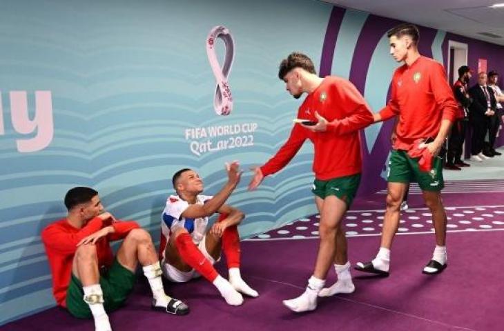 Potret membumi striker timnas Prancis, Kylian Mbappe, duduk tanpa alas bareng bek sayap timnas Maroko, Achraf Hakimi di lorong Stadion Al Bayt, Al Khor, Qatar usai laga semifinal Piala Dunia 2022, Kamis (15/12/2022). [Twitter/@@JacobsBen]