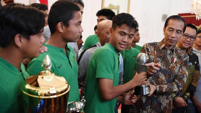 Presiden Joko WIdodo (kedua kanan) didampingi Menpora Imam Nahrawi (kanan) memegang piala bersama pemain Timnas U-16 di Istana Merdeka, Jakarta, Kamis (4/10). [ANTARA FOTO/Wahyu Putro]