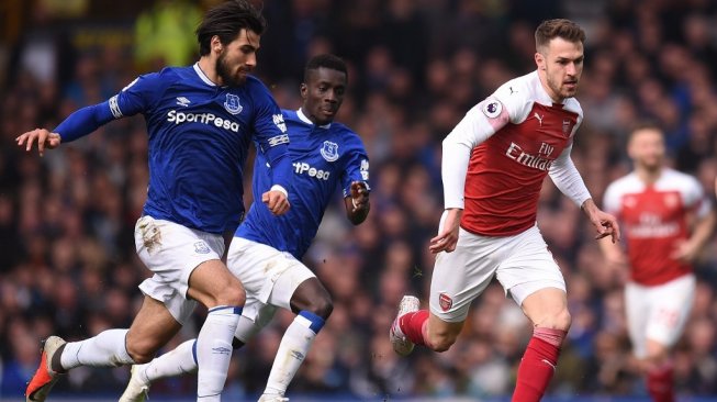 Gelandang Arsenal, Aaron Ramsey (kanan) dibayangi dua gelandang Everton, Andre Gomes (kiri) dan Idrissa Gueye (tengah) pada laga lanjutan Liga Inggris 2018/2019 di Goodison Park, Minggu (7/4/2019) malam WIB. [Oli SCARFF / AFP]