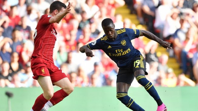 Penyerang baru Arsenal, Nicolas Pepe (Kanan) melakoni debut awalnya bersama tim saat menghadapai Liverpool di Stadion Anfield, Sabtu (24/8/2019). (BEN STANSALL / AFP)