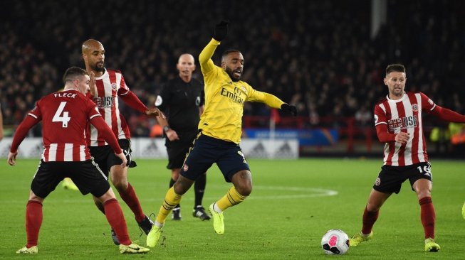 Penyerang Arsenal, Alexandre Lacazette terjatuh saat dilanggar pemain Sheffield United pada pertandingan Liga Primer Inggris 2019/20 di Stadion Bramall Lane, Selasa (22/10/2019). (OLI SCARFF / AFP)