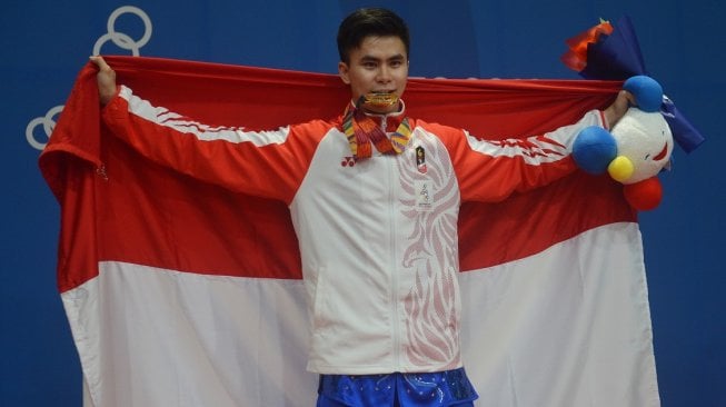 Atlet wushu Indonesia Edgar Xavier Marvelo menggigit medali setelah memenangi nomor gunshu putra SEA Games 2019 di gedung World Trade Center Manila, Filipina, Selasa (3/12). [Antara/Nyoman Budhiana]