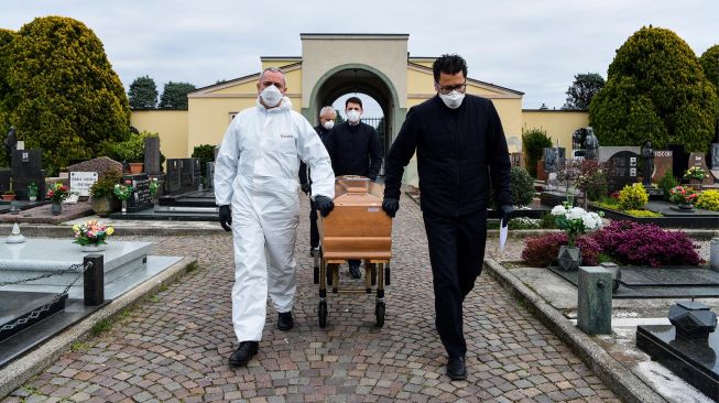 Pengurus jenazah membawa peti mati warga yang meninggal karena virus Corona di pemakaman Grassobbio, Lombardia, Italia, Selasa (24/3). [Piero CRUCIATTI / AFP]