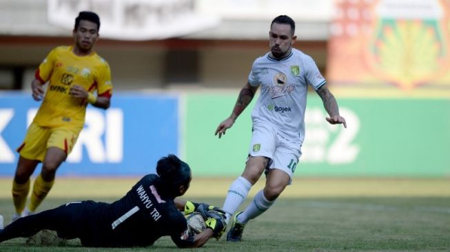 Penjaga gawang Bhayangkara FC Wahyu Tri Nugroho (tengah) mengangkap bola dari pesepak bola Persebaya Surabaya Damian Lizio (kanan) dalam lanjutan Liga 1 Indonesia di Stadion Patriot Chandrabhaga, Bekasi, Jawa Barat, Sabtu (31/8/2019). ANTARA FOTO/M Risyal Hidayat/hp. (ANTARA FOTO/M RISYAL HIDAYAT)