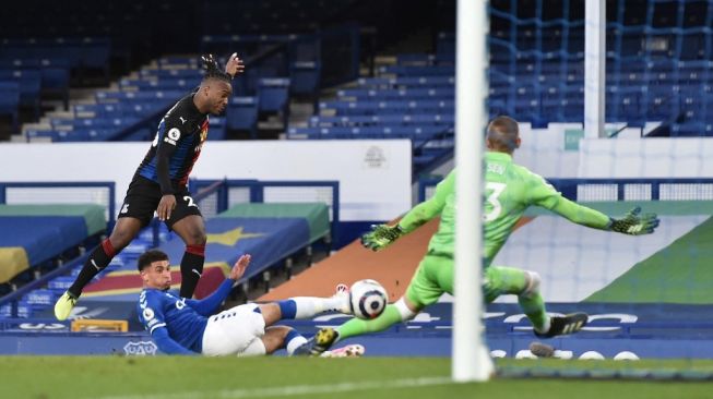 Penyerang Crystal Palace, Michy Batshuayi (kiri) melepaskan tembakan yang berbuah gol saat menghadapi Everton dalam laga pekan ke-30 Liga Inggris di Godison Park, Selasa (6/4/2021) dini hari WIB. [PETER POWELL / POOL / AFP].