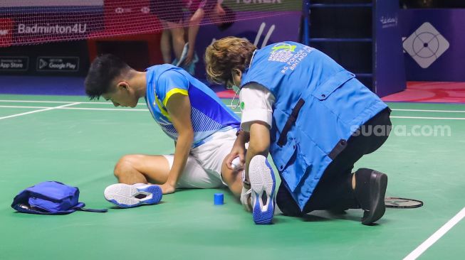 Pebulu tangkis ganda putra Indonesia Yeremia Erich Rambitan diperiksa tim medis usai mengalami cedera saat bertanding melawan pasangan ganda putra Malaysia Aaron Chia dan Soh Wooi Yik dalam babak 8 besar East Ventures Indonesia Open 2022 di Istora Senayan, Jakarta Pusat, Jumat (17/6/2022). [Suara.com/Alfian Winanto]