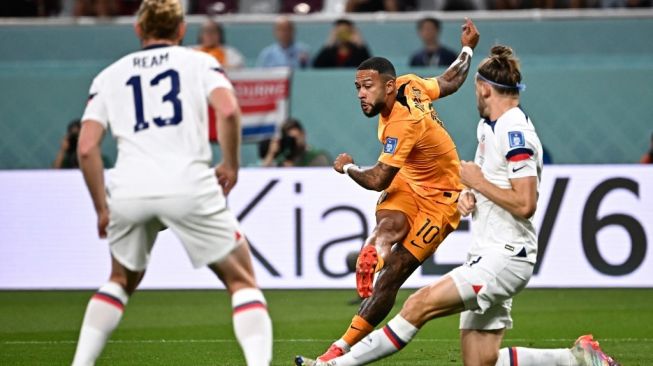 Penyerang Belanda #10 Memphis Depay (tengah) melepaskan tembakkan yang berbuah gol pertama timnya selama laga babak 16 besar Piala Dunia 2022 antara Belanda vs Amerika Serikat di Stadion Internasional Khalifa di Doha pada 3 Desember 2022.Anne-Christine POUJOULAT / AFP