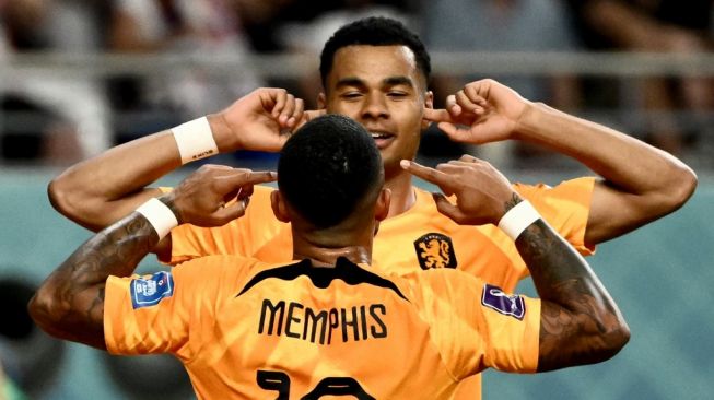 Penyerang Timnas Belanda #10 Memphis Depay (Depan) melakukan selebrasi dengan Cody Gakpo setelah mencetak gol pertama timnya selama laga babak 16 besar Piala Dunia 2022 antara Belanda vs Amerika Serikat di Stadion Internasional Khalifa di Doha pada 3 Desember 2022.Permata SAMAD / AFP.