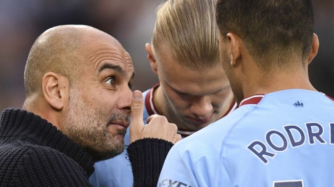 Manajer Manchester City Pep Guardiola (kiri) berbicara dengan striker Erling Haaland (tengah) dan gelandang Rodri selama pertandingan lanjutan Liga Inggris 2022-2023 antara Manchester City vs West Ham di Stadion Etihad di Manchester, barat laut Inggris , pada 3 Mei 2023.Oli SCARFF/AFP.